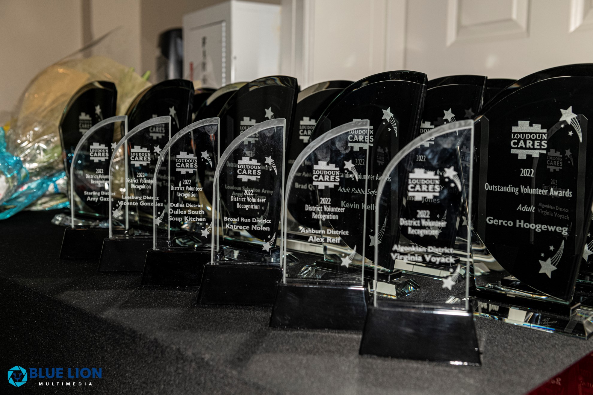 Dozens of clear glass trophies lined up on a table, each recognizing a 2022 Loudoun Cares volunteer